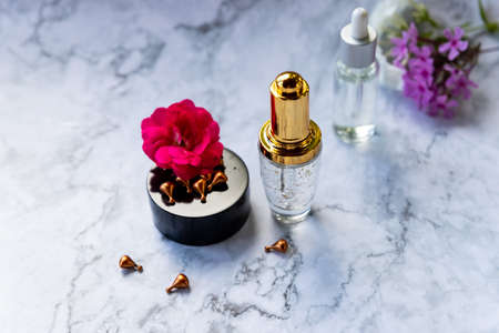 glass bottle with dropper,Moisturizing and healing skin serum with vitamin C on a marble background. Vitamin capsules as a supplement to a cream or essence for home care.Treatment facial essence oil,の写真素材