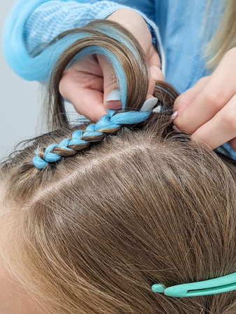 Thick breydy on the head of a girl from a blue kanekalon, artificial hair is woven into a pigtail.A girl with a fashionable set of blue braids Kanekalon.の写真素材
