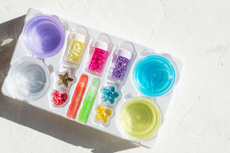 DIY slime. Ingredients and decorations for slime. Jars of sequins and beads.lilac , yellow and blue slime boxes, jar on white background. Kids toys, games. Education and leisure timeの写真素材