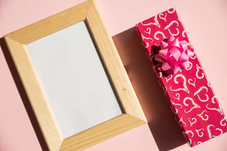 Happy Valentines Day with empty wooden photo frame, present box, gift on pink background. Valentine day, mother day, wedding anniversary concept. Top view with copy space.Minimal flat lay styleの写真素材