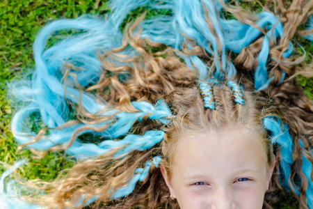 Portrait of beautiful girl with many braids with blue kanekalon.Cute girl 7 years old with braids on...