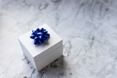 Christmas gift box or present with ribbon end bow isolated on grey marble background. Festive blue gift bow.Copy space for greeting text.の写真素材