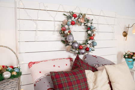 Christmas wreath made of fir branches, cones and Christmas toys on the wall.warm cozy modern design...