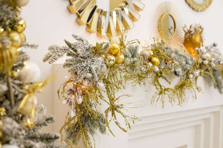 Luxury new year decor. Beige, golden, silver Christmas decoration. Merry Christmas and Happy Holidays. Festive interior with fireplace and decorations.golden baubles.Selective focusの写真素材
