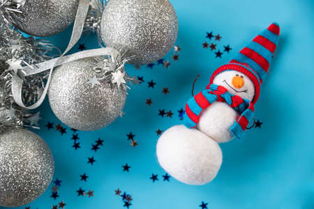 Christmas and New Year needle felted snowman in red blue knitted hat on blue background with silver christmas ornaments. home decor, toys and gifts.snowman dollの写真素材