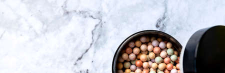 Brown rouge balls in the open round black plastic container isolated on marble background.の写真素材