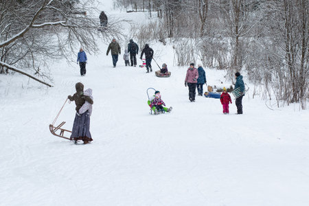 December 2, 2020. Omsk,Russia.People walk in snowy winter forest with their families, with skis, sleds, inflatable tubing, roll down hill, build snowman. Winter outdoor activities.Winter funのeditorial素材