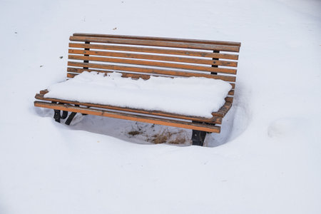 Park bench covered by heavy snow.lonely wooden bench under snow fall. snowfall day. Perfect for christmas holidaysの写真素材