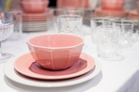 Commercial pink and white plates and bowls stacked with crystal wine glasses.Colorful ceramic clean dishware.Ceramic crockery tablewareの写真素材