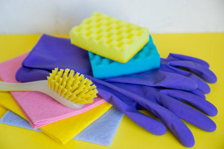 Set of plastic bottles of different cleaning procucts, rubber gloves and sponges on white background...