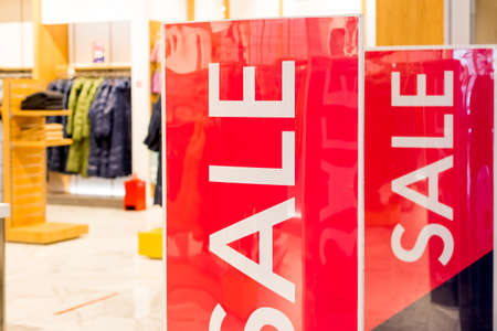 Red bright sale banner on anti-thieft gate sensor at retail shopping mall entrance. Seasonal discount offer .Discount information at store entrance, shopping season promotion.Large red panels.の写真素材