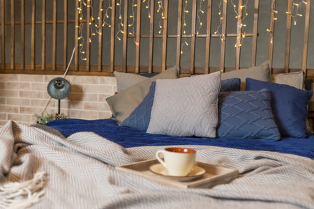 coffee cup or hot tea in the morning on the bed background.Bedroom view. Grey and blue linen pillows...