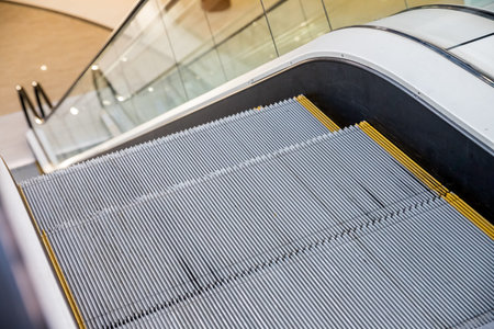 modern escalators,Gray metal textured steps, black handrail. Clear acrylic or plastic sides.Escalator in shopping center, or office building, or subway station.の写真素材