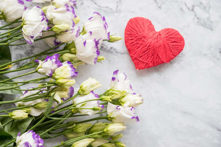 Minimal composition with a Eustoma flowers and red heart on marble background, top view. Valentines day, mothers day greeting card.copy spaceの写真素材