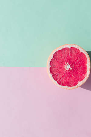 Fresh sliced ripe Grapefruit on green and pink background, top view. halved grapefruit.Flat lay design Vegan Art.Fresh lemonade concept. Creative summer background.の写真素材