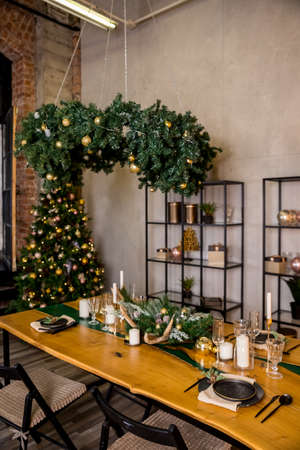 Festive table setting with rustic decorations for Christmas. New Year holidays, celebration, decorations in modern interior design.tableware, eco style,candles with warm fires and conifers brunchesの写真素材