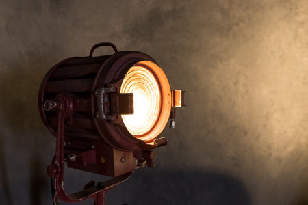 Old movie projector with a lens and a hot lamp.Vintage lamp projector near the grey wall. Room in loft style.Interior design. Metallic projector lantern.cinematic lamp studio, light searchlightの素材 [FY310170753915]