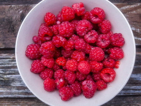 Closeup of bowl of fresh and ripe rasberries on wooden table. natural food.Ripe tasty...