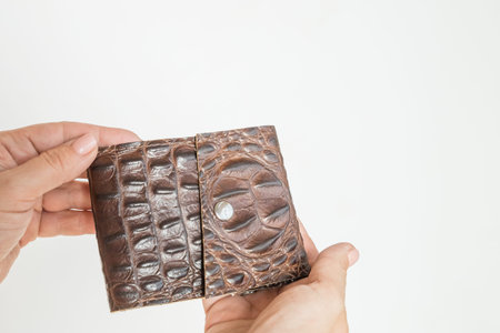 Hand holding leather brown wallet purse isolated on white background. Handmade wallet for money and...