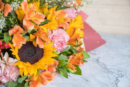 Fresh Bouquet of yellow sunflowers and pink carnations on marble background. flower shop. A variant of a bouquet on an autumn theme, for Thanksgiving.の写真素材