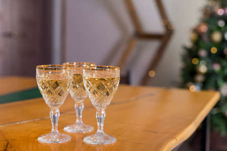 Corporate party: sparkling champagne glasses on wooden table.New Year picture of three glasses with wine on christmas tree backgroundの写真素材