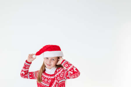 portrait of happy girl dancing ,wearing red christmas sweater and santa hat isolated on white background.young caucasian joyful smiling blonde girl in a Christmas red deer sweater is happy.の写真素材