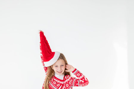 portrait of happy girl dancing ,wearing red christmas sweater and santa hat isolated on white background.young caucasian joyful smiling blonde girl in a Christmas red deer sweater is happy.の写真素材