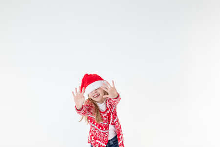 portrait of happy girl dancing ,wearing red christmas sweater and santa hat isolated on white background.young caucasian joyful smiling blonde girl in a Christmas red deer sweater is happy.の写真素材