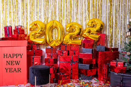 2022 inflatable golden balloons and glittering decorations. New Years concept.Balloons made of gold foil with presents and confetti. Party decoration. Text happy new yearの写真素材