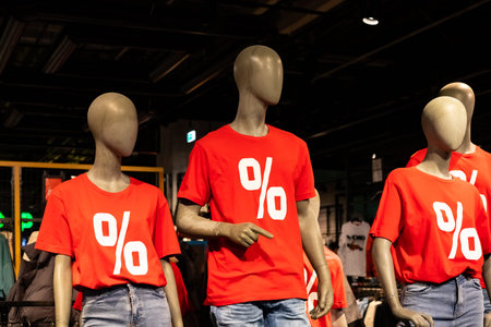 three dummy mannequin models wearing red shirts with white text percent sign.sale of fashion...