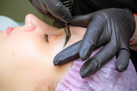 Cosmetologist applying permanent makeup on eyebrows Selective focus and shallow Depth of...