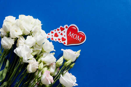 Happy Mothers Day greeting card with spring flowers and decorative heart on blue background.flower composition, Greeting Card.inscription Mom and red heart.の写真素材