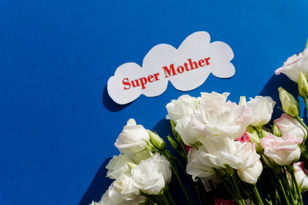 Happy Mothers Day greeting card with spring flowers and decorative heart on blue background.flower...