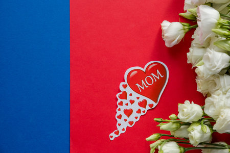 Happy Mothers Day greeting card with spring flowers and decorative heart on red blue background.Design concept - top view of bunch of beautiful eustoma flowersの写真素材