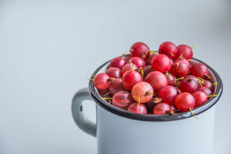 Set of organic Gooseberries fruits in a cup. red gooseberry over white background. Sweet and juicy berry. healthy summer food. they are good for vision, immunity, cognitive abilitiesの写真素材
