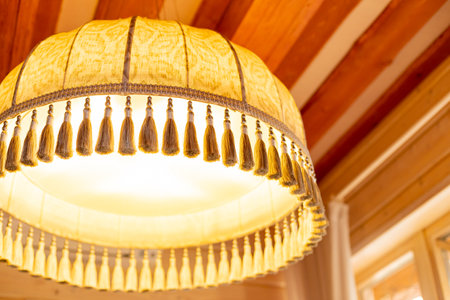 Large yellow fabric lampshade with fringe as an element of vintage decor. Old style retro lamp shades.Textile decor for chandeliers.decorative lamp hanging in the rooomの写真素材