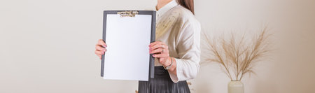 Woman holding clipboard with a blank sheet of paper. Blank paper poster in female hands. Blank template for graphic designers portfolios. To do plans in business, blogging, educationsの写真素材
