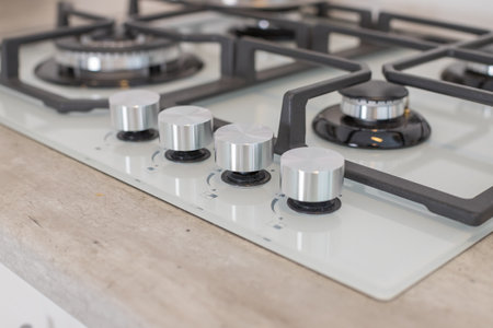Modern hob gas stove made of tempered white glass using natural gas or propane for cooking products on light countertop in kitchen interior.Industrial resources and economy concept.の写真素材
