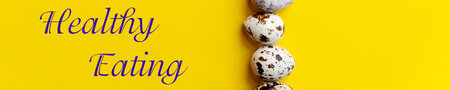 fresh Spotted Quail eggs in a row.Organic eggs on yellow table. Healthy food concept. web banner.Top view, copy space. Selective focus. text healthy eatingの写真素材