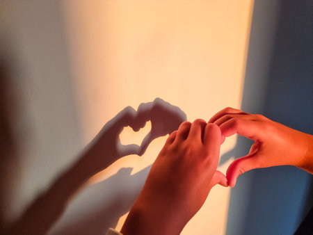Silhouette of a girl making heart. sun and shadow.love,hope and kindness concept.Child playing with shadow on wall, having fun. copy spaceの写真素材