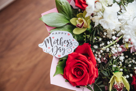 Happy Mothers Day text on gift card with flower bouquet of roses, orchids, chrysanthemums. Greeting card for Mom. Flower delivery, Congratulations, surprise for mother.の写真素材