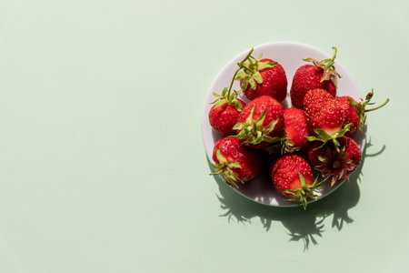 Heap of fresh strawberries in ceramic bowl on pastel green background.Healthy food. Delicious, sweet, juicy and ripe berry background with copy spaceの写真素材