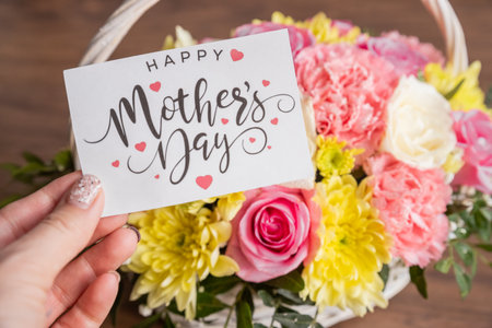 hand with mothers day greeting card - Beautiful blooming flowers in basket.Creative bouquet with chrysanthemums, roses, carnations.floral presentの写真素材