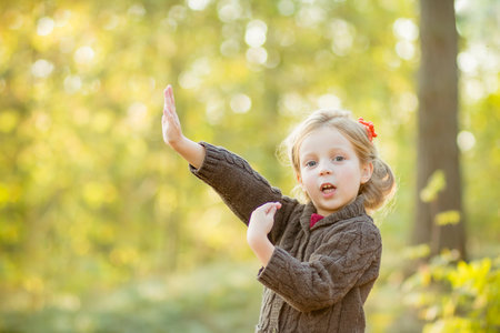 happy little child, girl 4-5 year old playing outdoor. Girl is wearing warm jacket. she is dancing, jumping,spending a weekend in autumn park. Autumnal mood.Childhood. Autumn season.の写真素材