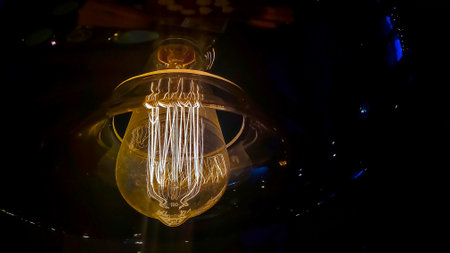 Vintage lightbulb on dark background with bright yellow shining wire.Close up of industrial lamp light.Illumination edison retro lamp on dark background.の写真素材