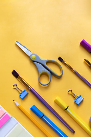 Back to school concept. Colorful stationary school supplies, copy space.Various stationery items on a yellow background. Paperclips. Clips for paper. Brushesの写真素材