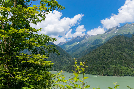 View through the trees on the lake between high and rocky mountains. Beautiful landscape.wild landscape.Scenic hiking views from Hill to green water lakeの写真素材