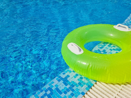 Bright inflatable tube ring floating on blue water surface, in swimming pool during sunny day.bright clear pool water. summer holidays. copy spaceの写真素材