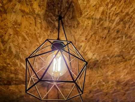 Black minimalist lamp in interior. Loft lamps, vintage, retro, scandi style. Edisons light bulb with warm tone light.Interior decoration of stylish housing. Loft style incandescent lamp.の写真素材