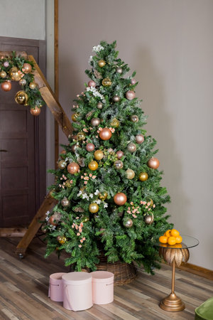 Christmas holiday decorations with lights and garland. Decorated Christmas tree with sparkling pink and golden baubles,lights, pink bow and glitter balls. Holiday present boxes. new yearの写真素材